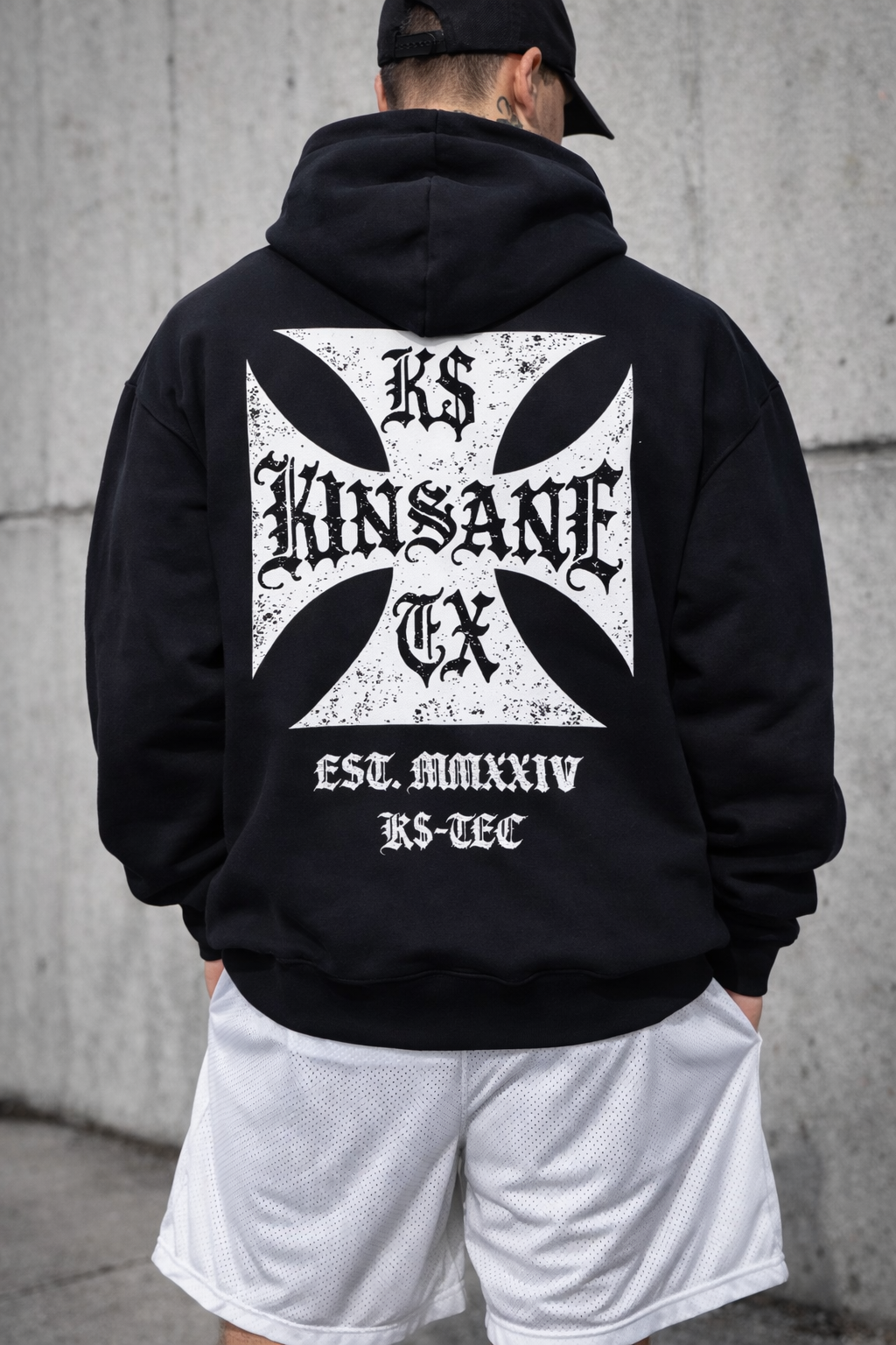Back view of a man wearing a black hoodie with a white logo with black lettering reading “KINSANE, K$, TX” and white text reading “EST. MMXXIV, K$-TEC” 