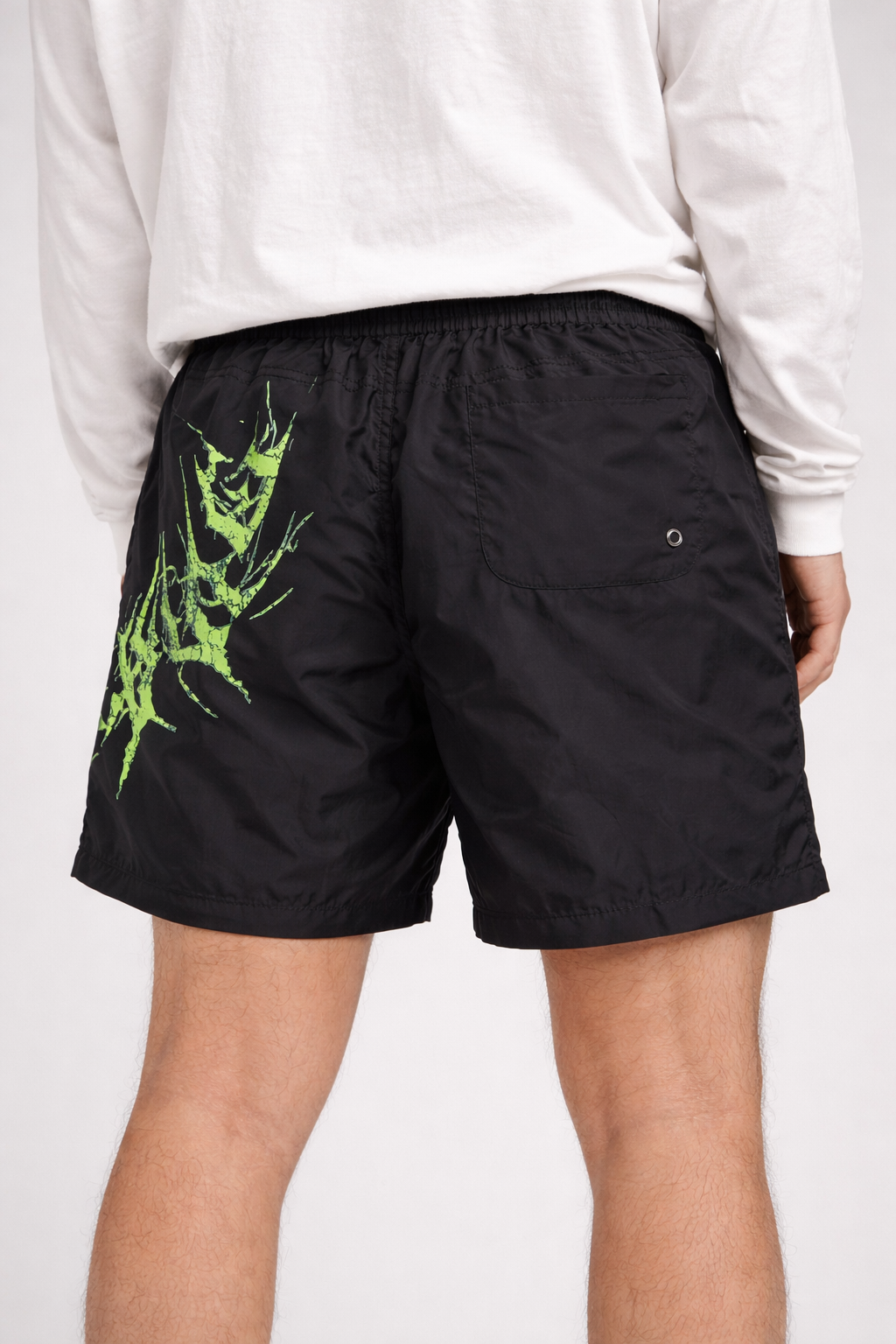Back view of man wearing Black shorts with black drawstrings and neon green lettering on the left leg reading “KINSANE”