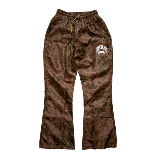 Brown camo sweatpants with green drawstrings and white text reading “KINSANE” and another white text reading “MMXXIV” on the left leg
