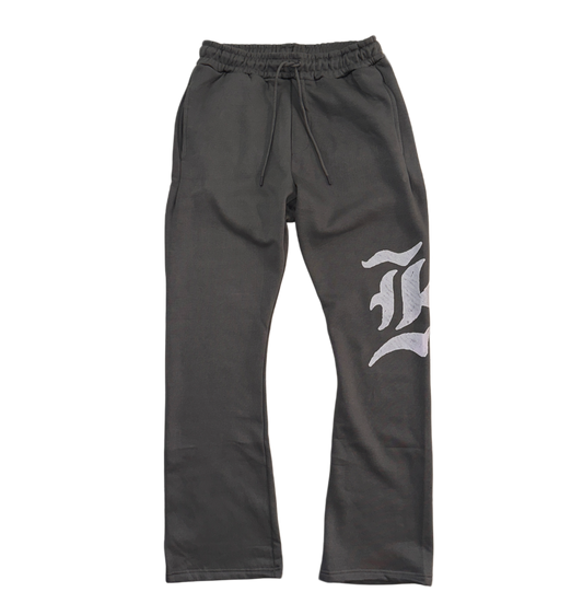 Gray stacked sweatpants with gray drawstrings and a white logo of a “K” on the left leg