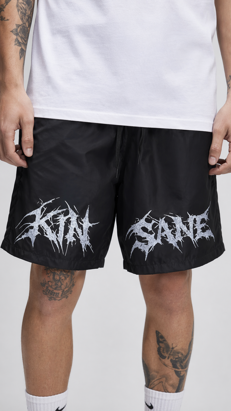 Man wearing Black shorts with black drawstrings and white lettering reading “KINSANE” 