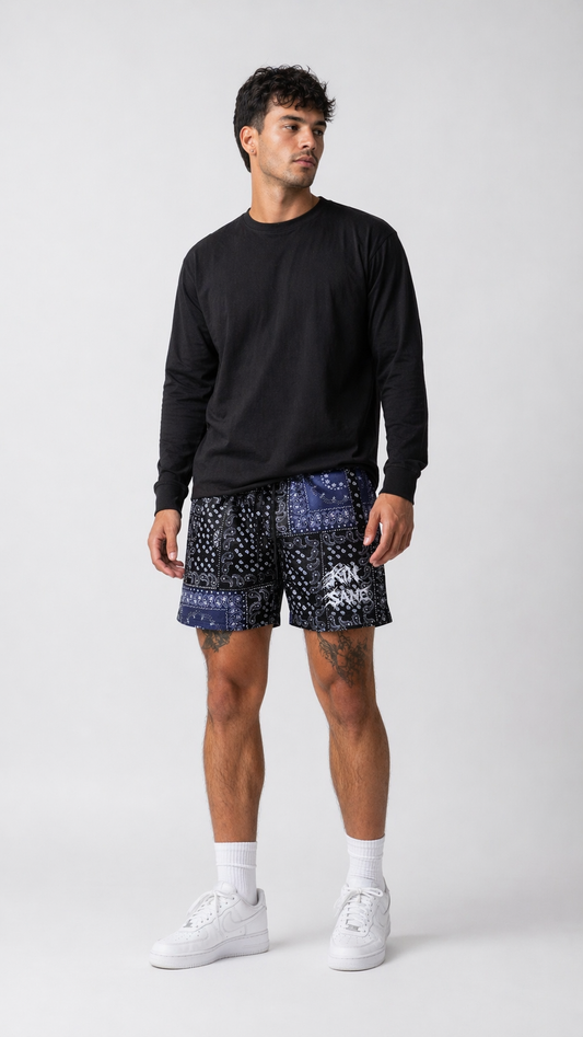 Man wearing Black shorts with white and blue bandana design and black drawstrings and white lettering reading “KINSANE “ on the left leg 