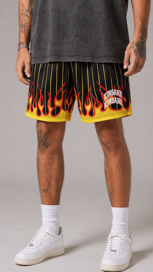 Man wearing Black and yellow shorts with flames design and two stacked white text reading “KINSANE” 