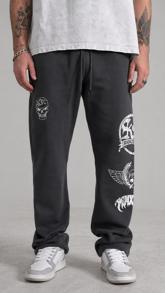 Ma wearing Gray stacked sweatpants with white skull logo on the right leg and white logos stacked on top of each other on the left leg that say “KS WORLDWIDE, MMXXIV” 