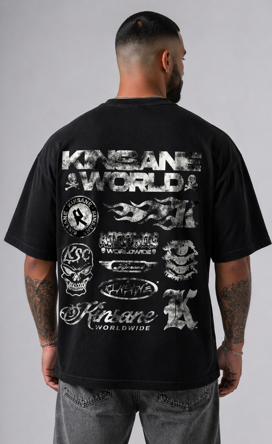 Back view of a man wearing a black t-shirt with multiple white kinsane themed logos reading “KINSANE” stacked on top of each other and white text reading “KINSANE WORLD” 