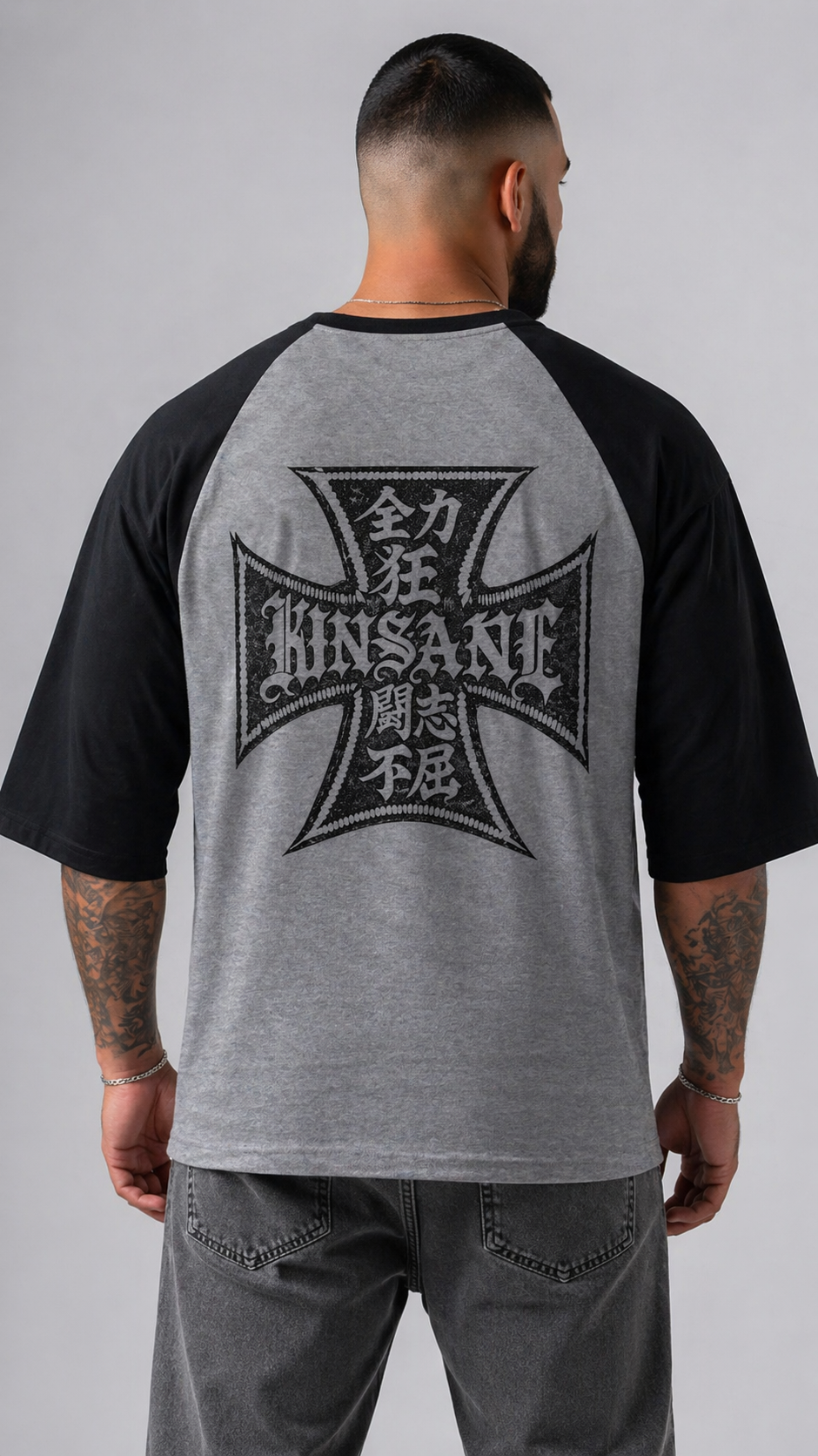 Back view of man wearing black and gray baseball raglan shirt with black logo with Japanese text and text reading “KINSANE” 