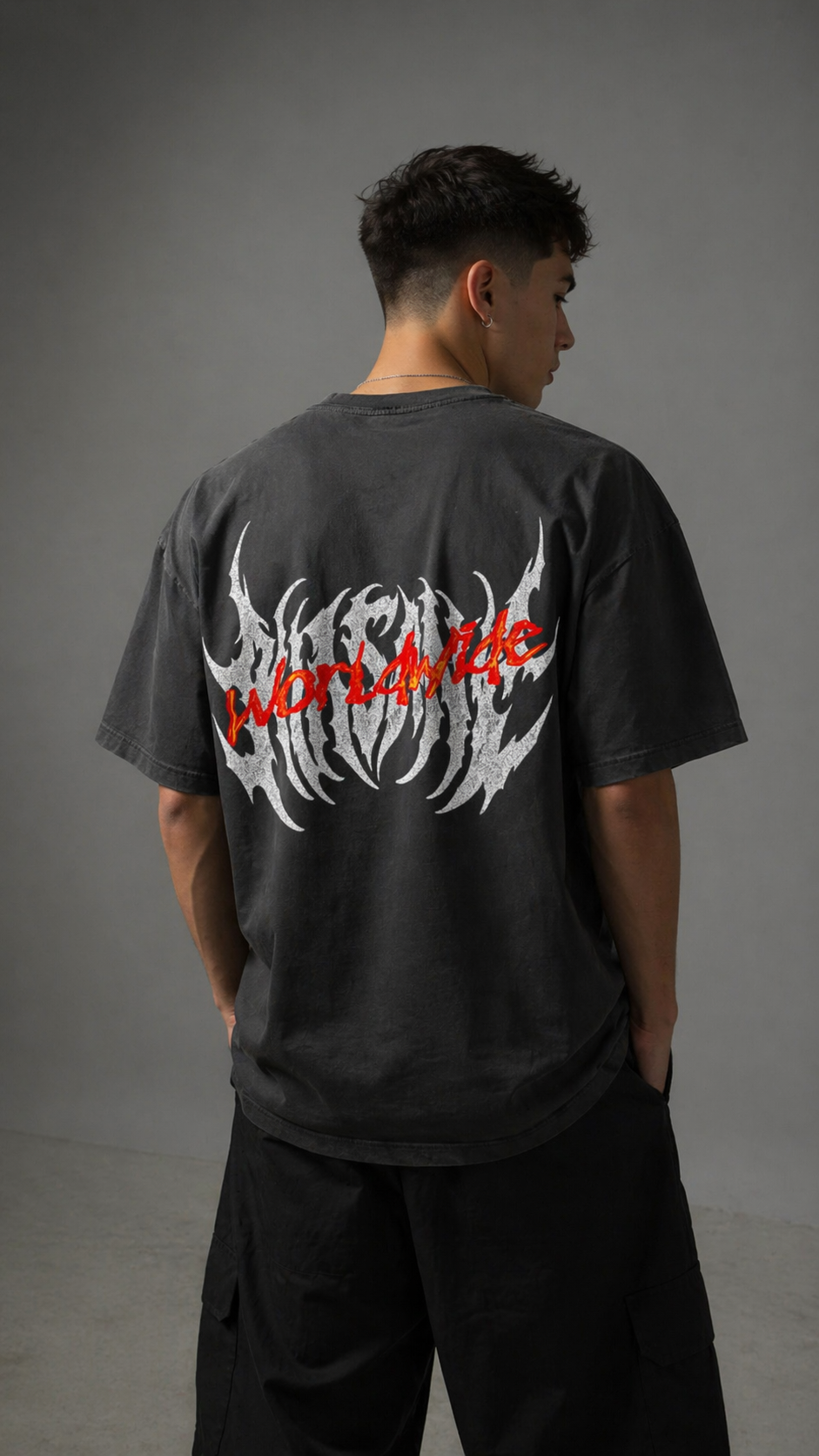 Back view of a man wearing a gray t shirt with grayish white text reading “KINSANE” and red-orange text reading “WORLDWIDE”  