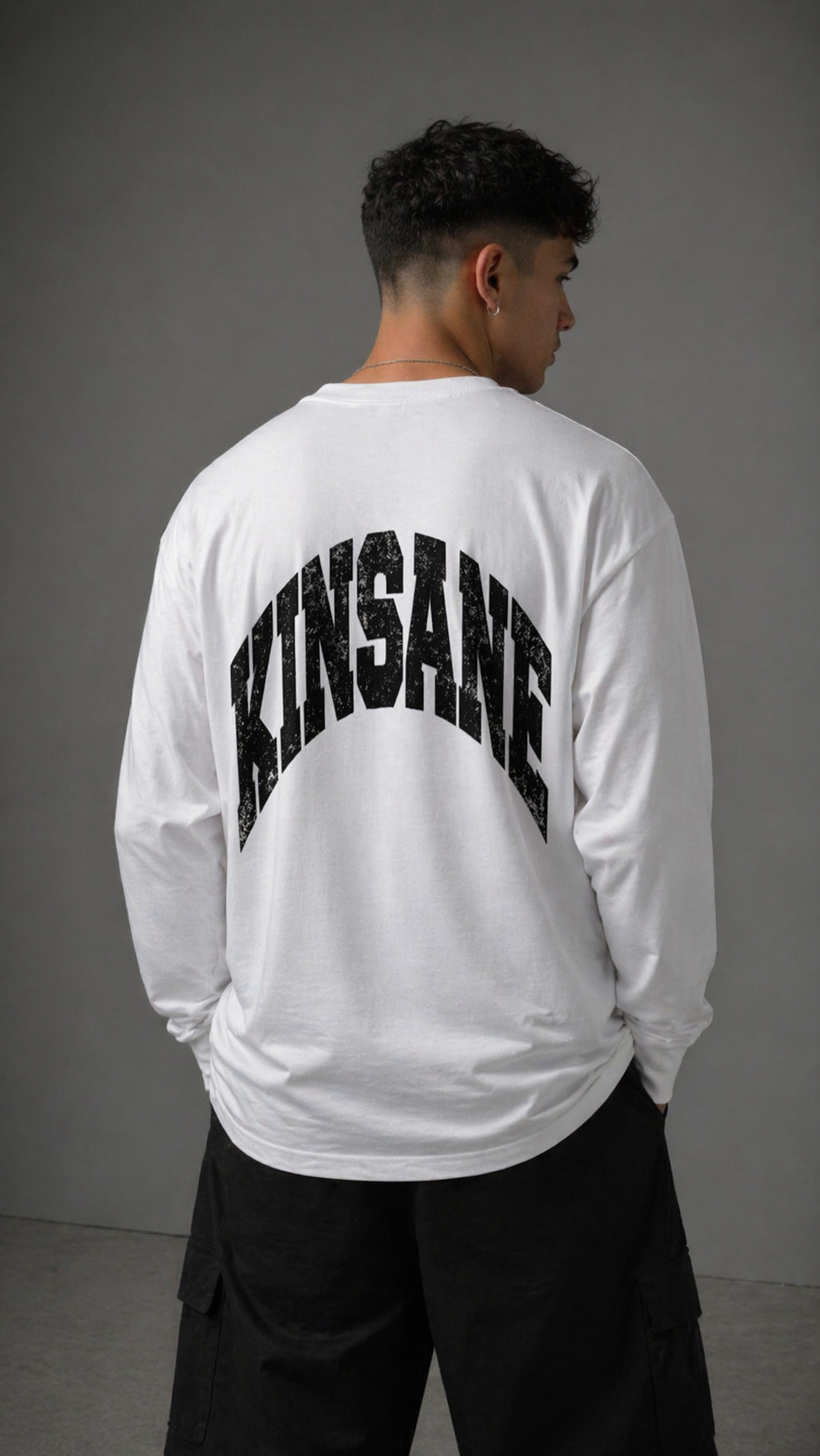 Back view of a man wearing a white long sleeve shirt with black text reading “KINSANE” 