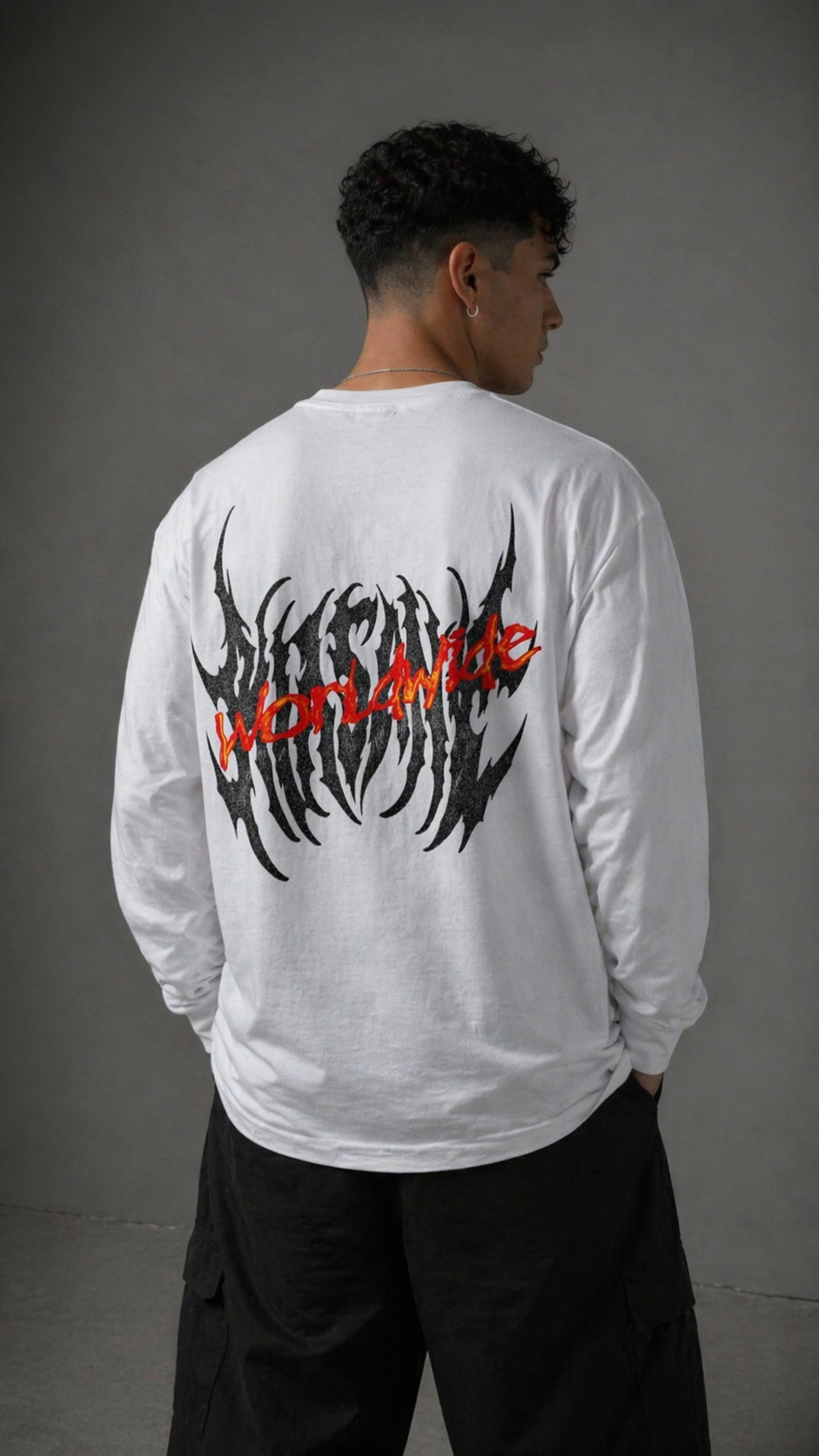 Back view of a man wearing a white long sleeve shirt with black text reading “KINSANE” and red text reading “WORLDWIDE” 