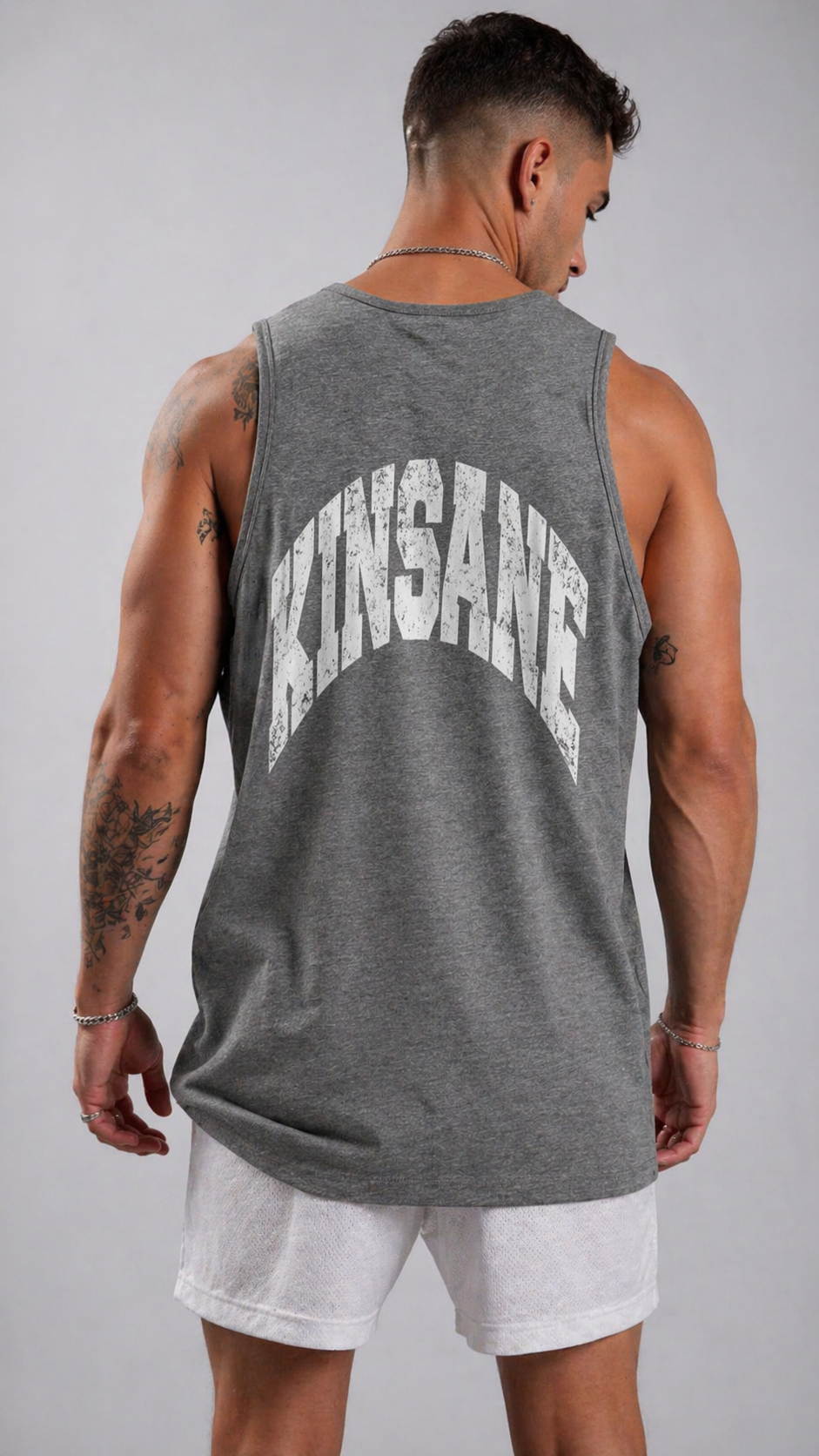 Back view of a man wearing a gray tank top with white text reading “KINSANE” 