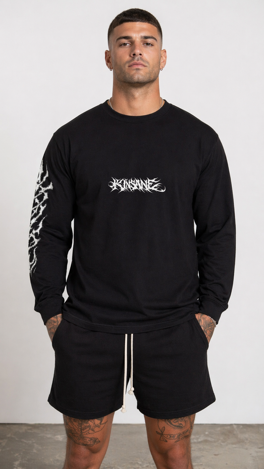 Man wearing a Black long sleeve T-shirt with white tribal lettering reading “KINSANE” in the center and white tribal designs on the right sleeve 