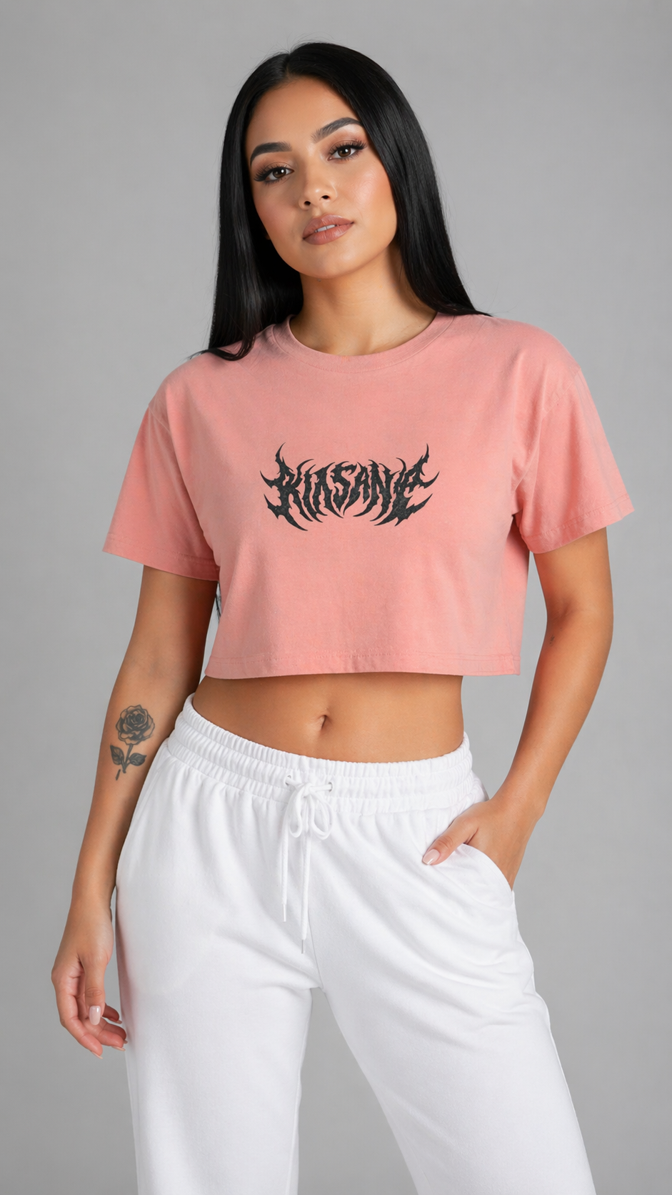 Girl wearing a Pink cropped top shirt with black lettering reading “KINSANE” 