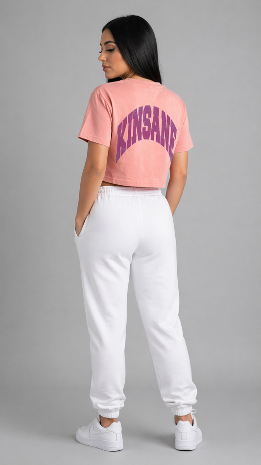 Back view of a girl wearing a pink cropped top t shirt with purple text reading “KINSANE” 