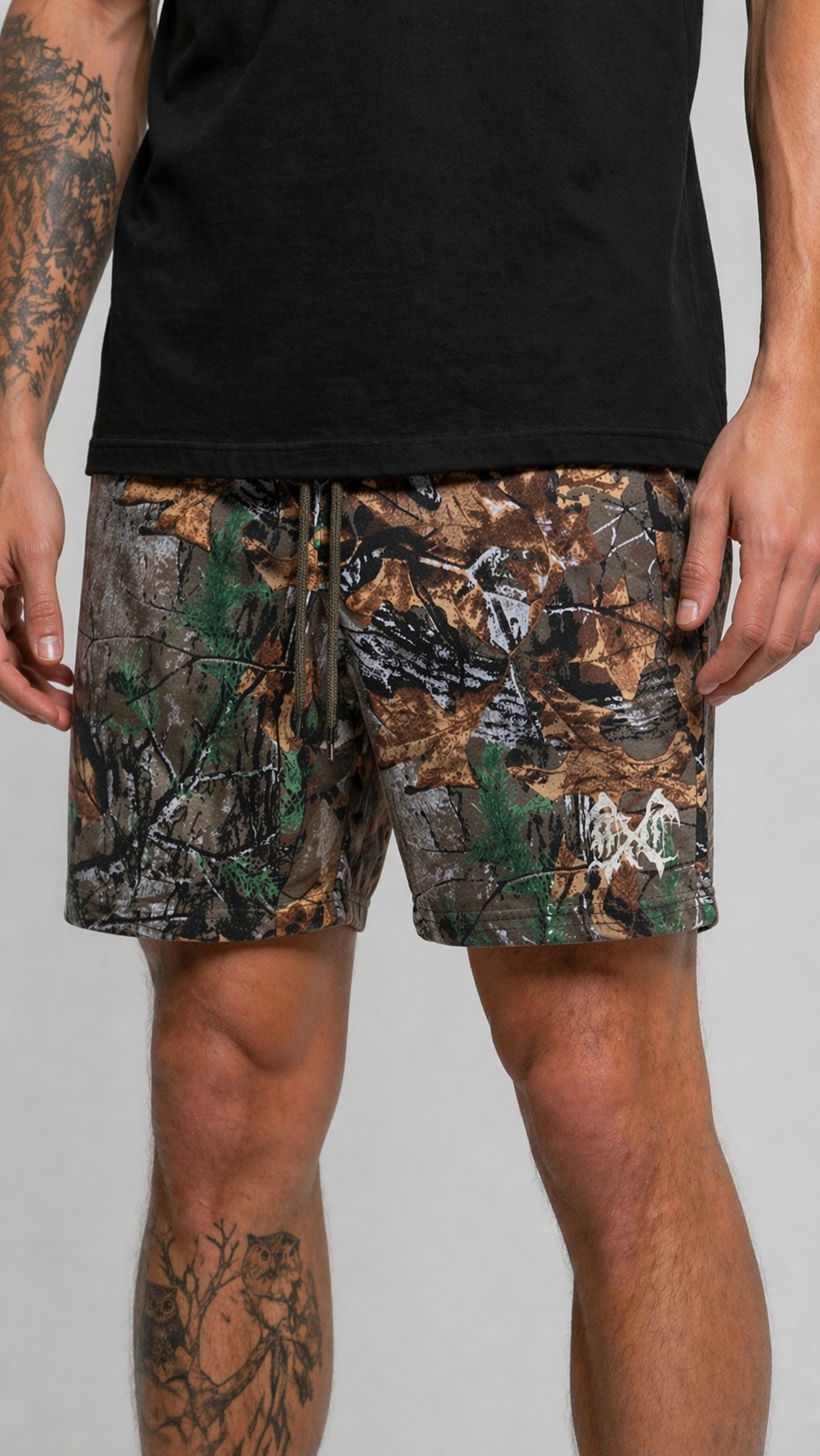 Man wearing Camouflage shorts with green drawstrings and white logo on the left leg 