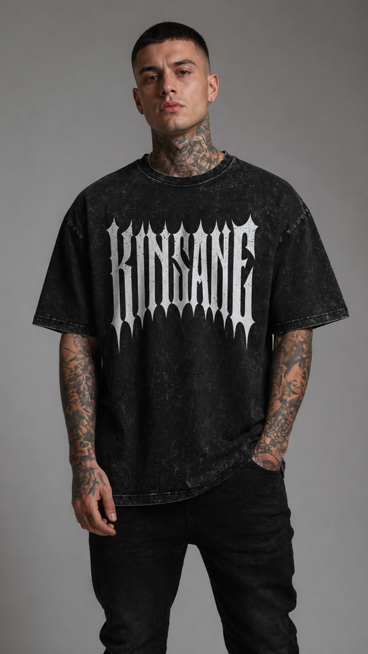 Man wearing Black acid washed t-shirt with silver spiked lettering reading “KINSANE” 