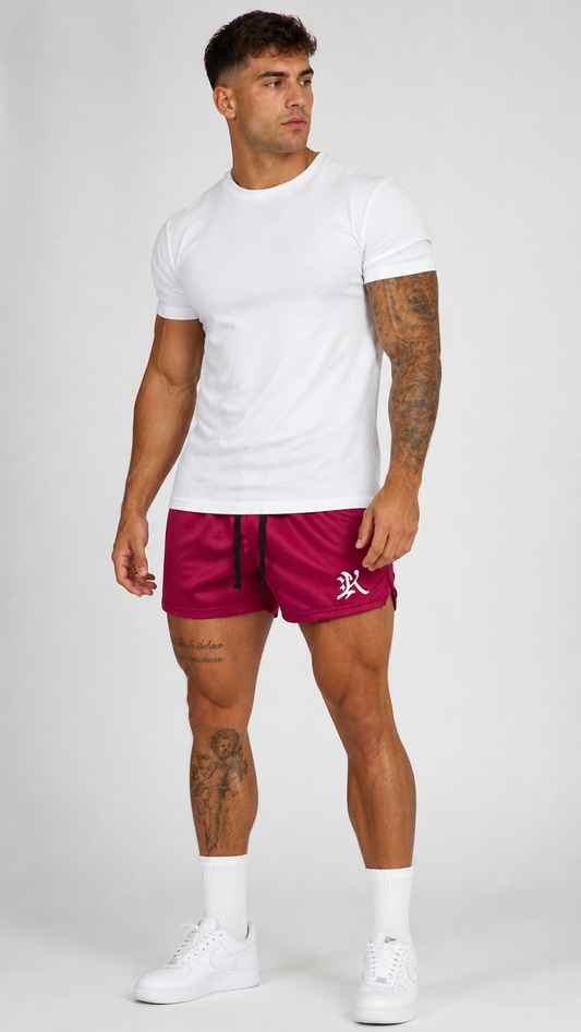 Man wearing Maroon athletic shorts with black drawstrings and a white logo of the letter “K” on the left leg 