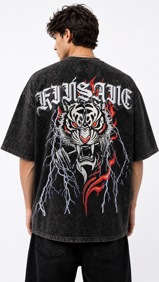 Back view of a man wearing a black acid washed t-shirt with a tiger in flames and lightning holding a dumbbell in its mouth design and white lettering reading “KINSANE”