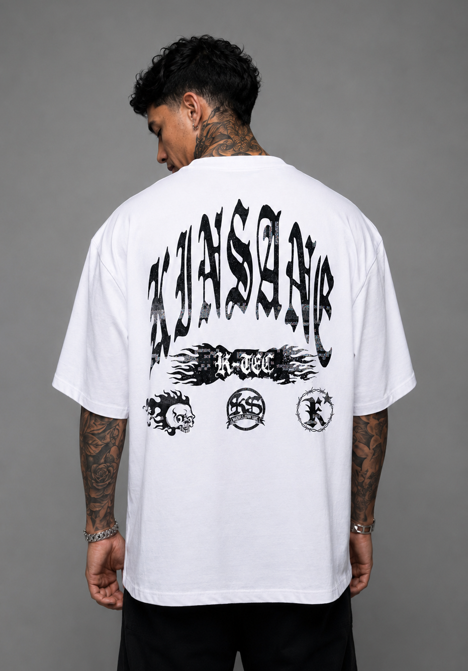 Back view of a Man wearing white t shirt with black text reading “KINSANE” and a black flamed logo reading “K-TEC” and three smaller black logos 