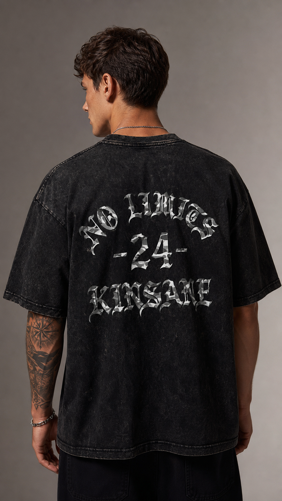 Back view of a man wearing a black acid washed t shirt with camo filter text reading “NO LIMITS -24- KINSANE” 
