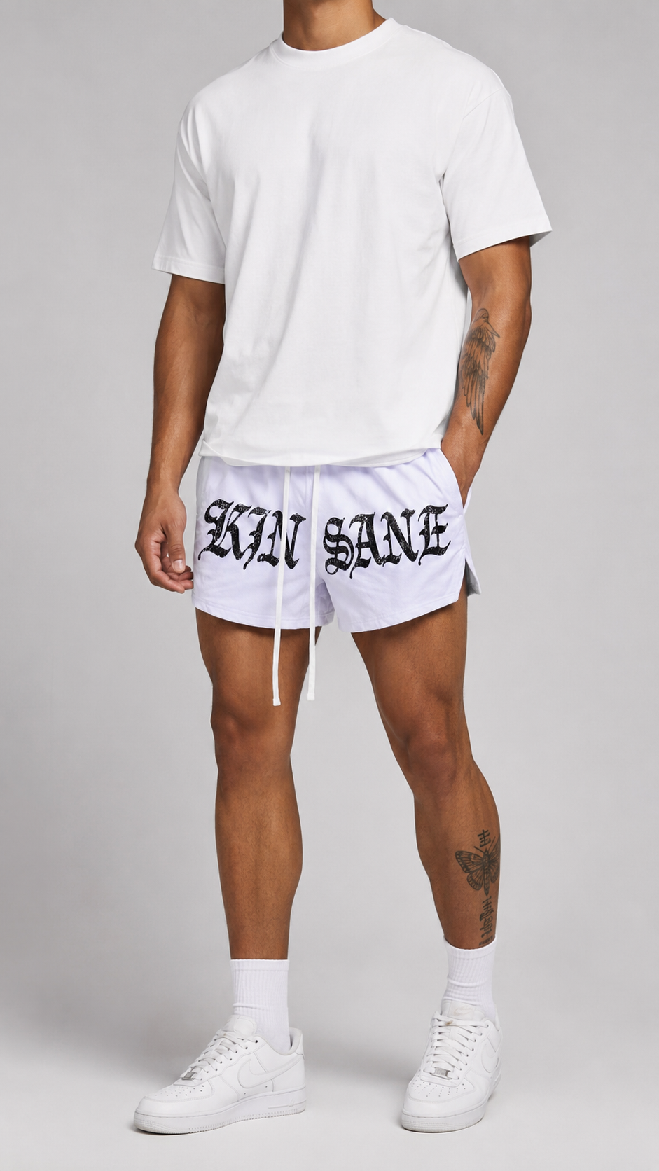 Man wearing White athletic shorts with white drawstrings and black lettering reading “KINSANE” on the front 