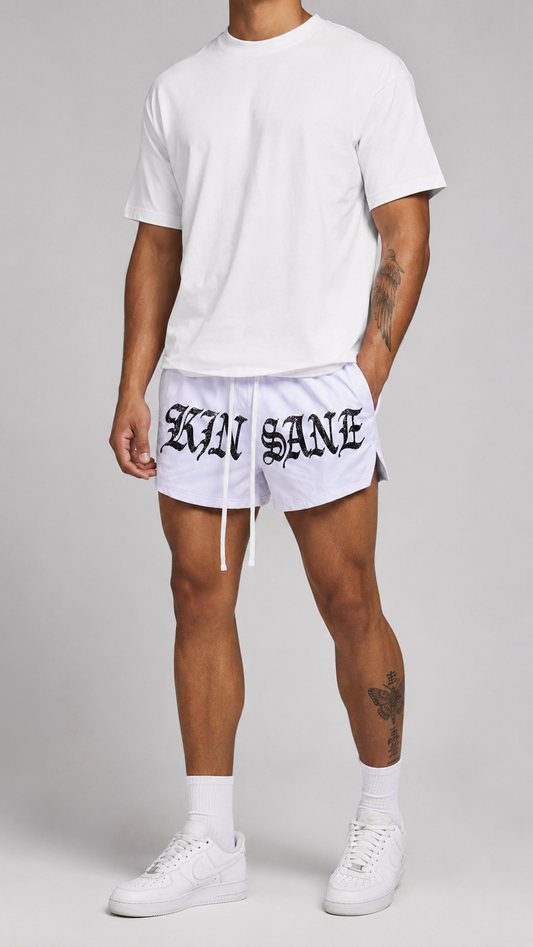 Man wearing White athletic shorts with white drawstrings and black lettering reading “KINSANE” on the front 