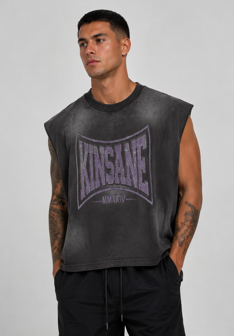 Man wearing Gray acid washed sleeveless shirt with grayish logo and lettering reading “KINSANE MMXXIV” 