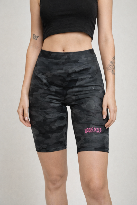 Girl wearing Black and grey camo compression shorts with pink old English style lettering reading “KINSANE” on the right side 