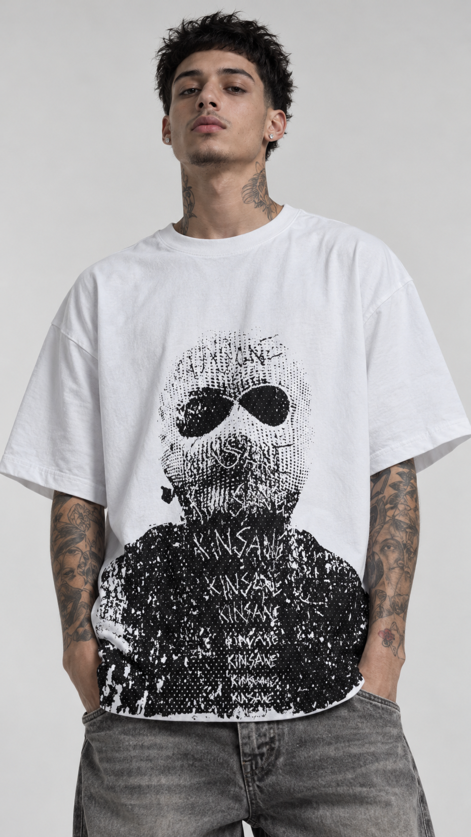 Man wearing White t shirt with gray and black design of a man wearing a ski mask with “kinsane” scratched on it 