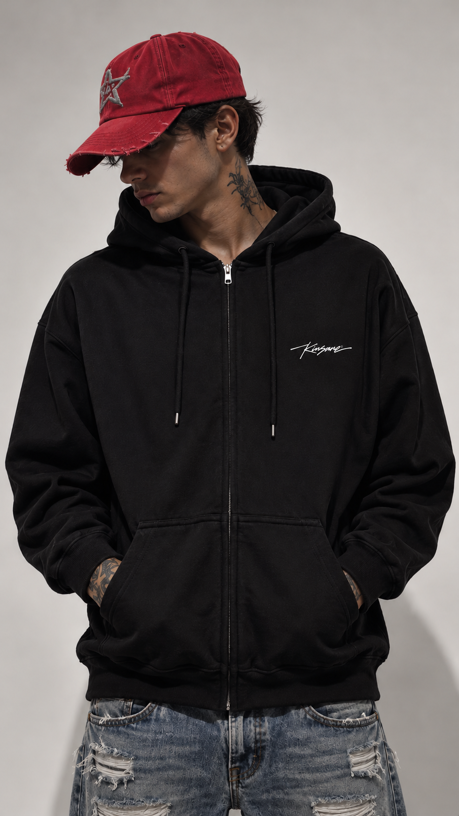 Man wearing Black zip up hoodie with small white cursive text on the right side reading “Kinsane ®️”