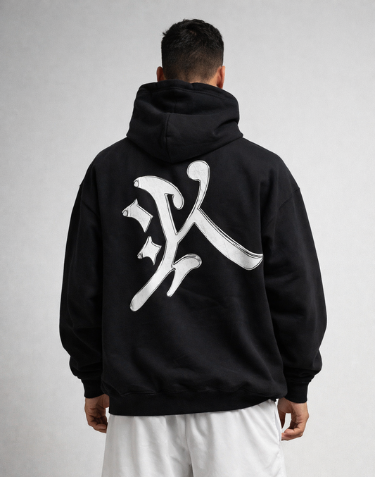 Back view of a man wearing a black hoodie with a silver letter “K” logo 
