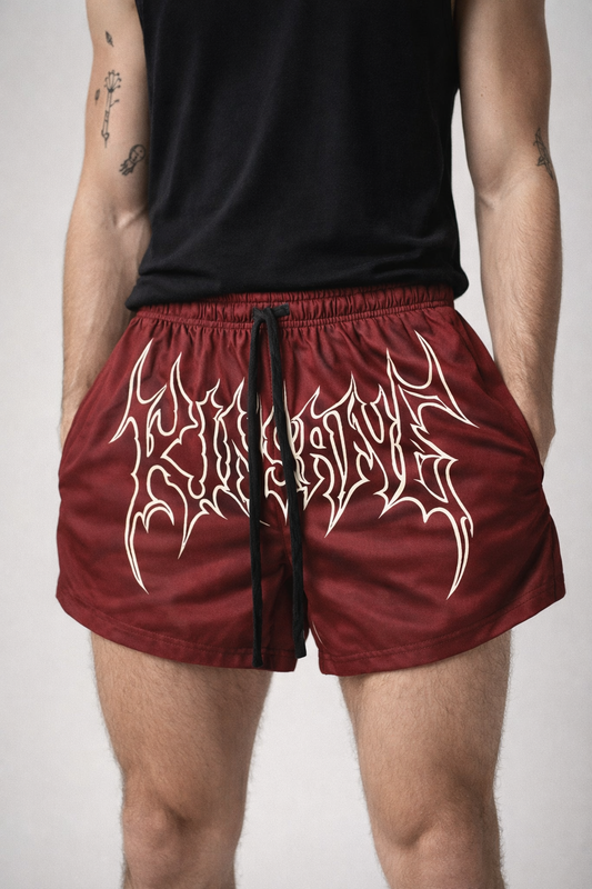 Man wearing Maroon athletic shorts with black drawstrings and white outlined lettering across the front reading “KINSANE” 