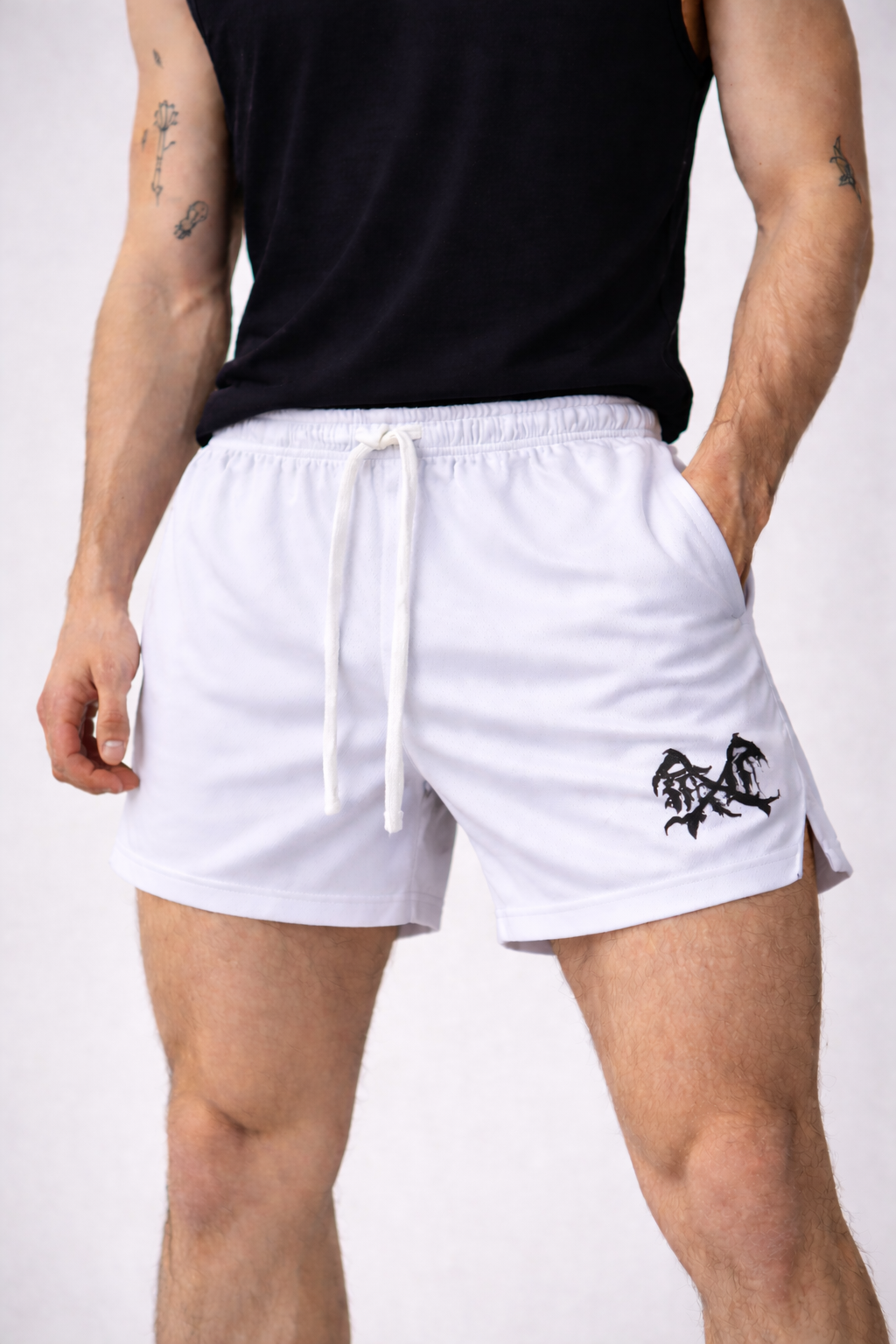 Man wearing White athletic shorts with white drawstrings and a black logo on the left leg 
