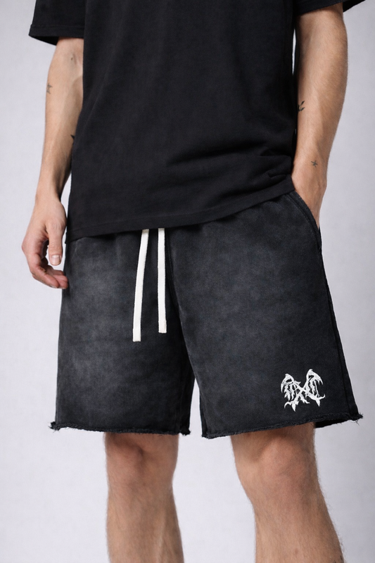Man wearing Black acid washed shorts with white drawstrings and white logo on the left leg 