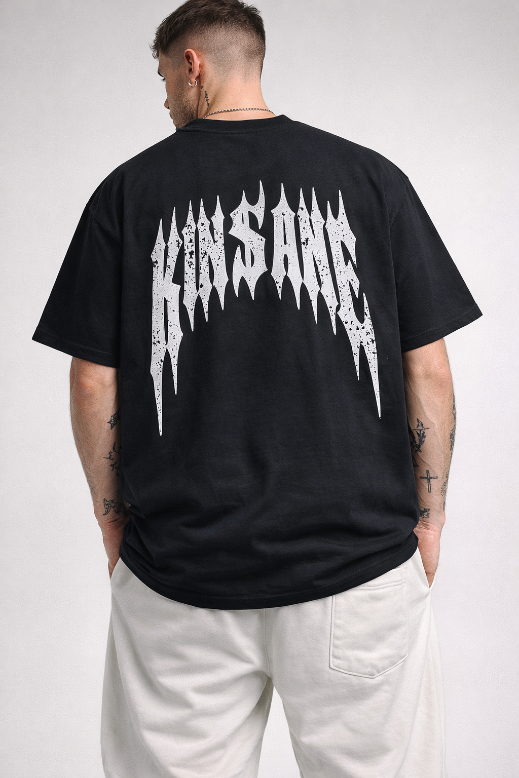 Back view of man wearing a black t-shirt with white distressed text reading “KINSANE” 
