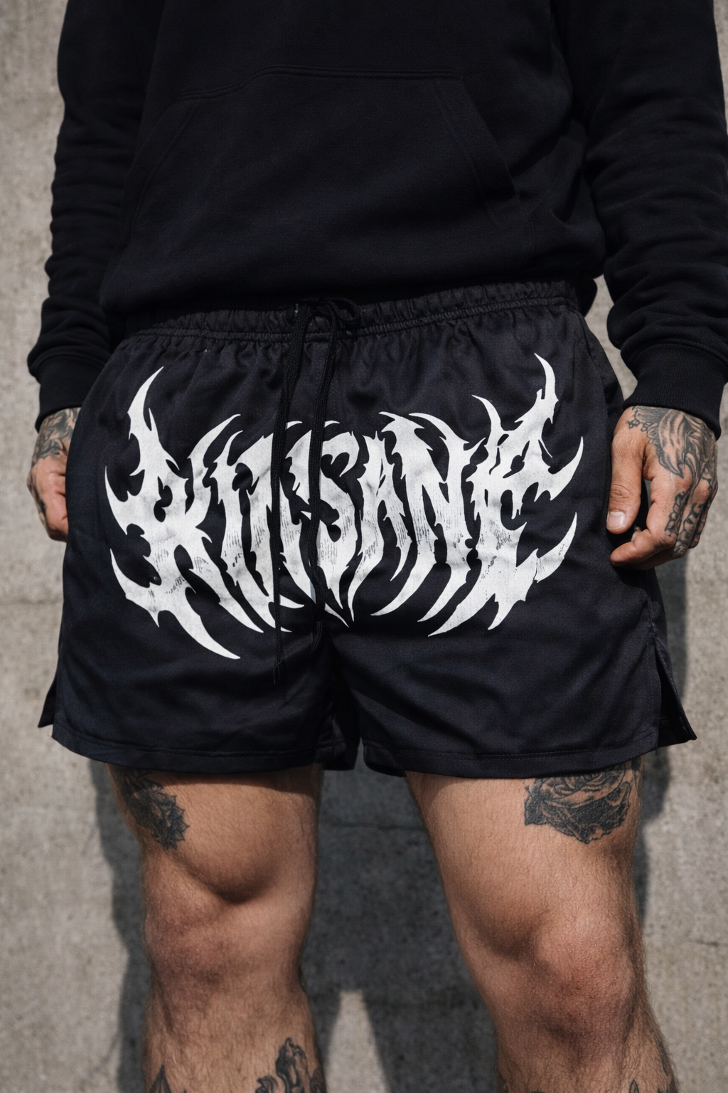 Man wearing Black athletic shorts with black drawstrings with white text reading “KINSANE” 