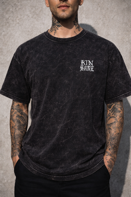 Man wearing a Black acid washed t shirt with white lettering reading “KINSANE” 