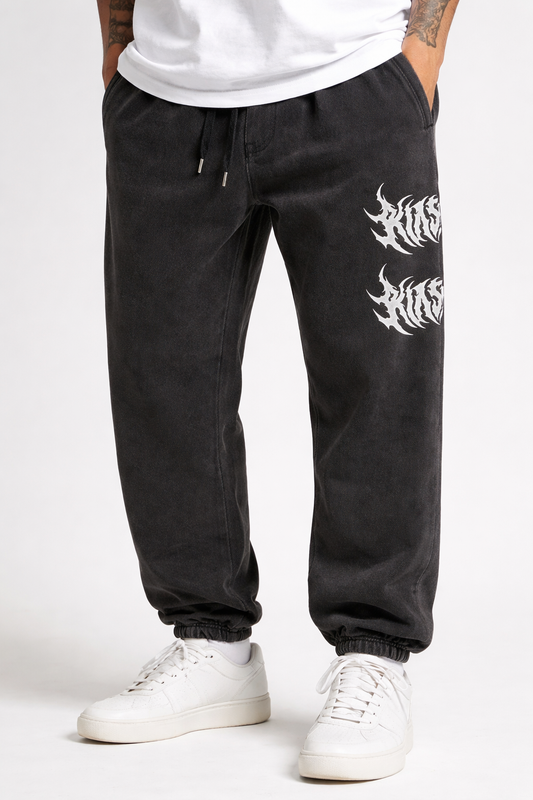 Man wearing Vintage grey cuffed joggers with white text reading “KIN” on the front left leg